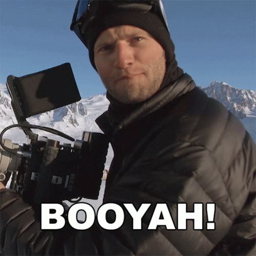 A Man Holding A Camera With The Word Booyah Written On The Bottom GIF