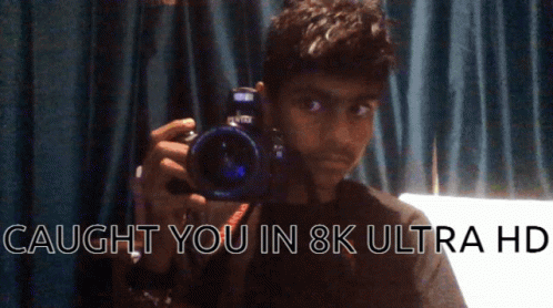 A Man Holding A Camera With The Words Caught You In 8K Ultra Hd On The Bottom GIF