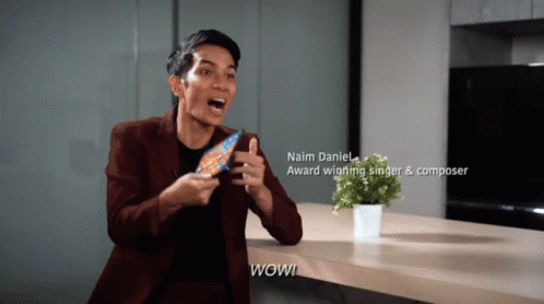 A Man Holding A Candy Bar With The Name Naim Daniel On The Bottom GIF