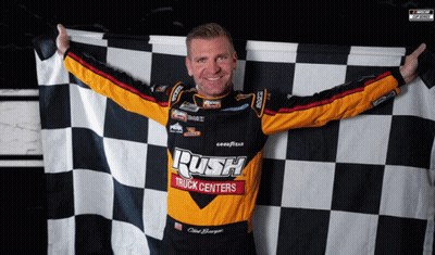 A Man Holding A Checkered Flag That Says Rush Truck Centers On It GIF