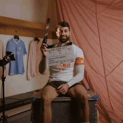 A Man Holding A Clapper Board That Says Feel Good Cats On It GIF