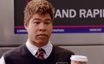 A Man Holding A Cup Of Coffee In Front Of A Sign That Says Rapid GIF