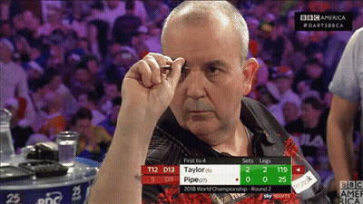 A Man Holding A Dart In Front Of A Scoreboard That Says First To 4 GIF