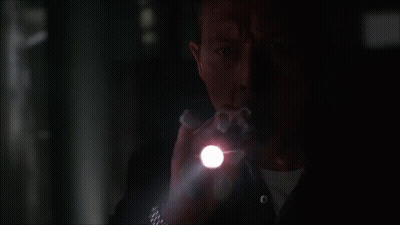 A Man Holding A Flashlight In The Dark GIF