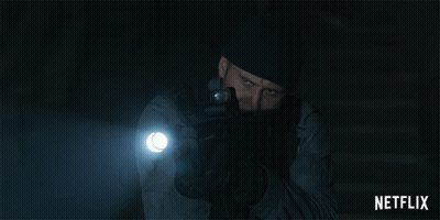 A Man Holding A Gun And A Flashlight With A Netflix Logo In The Corner GIF