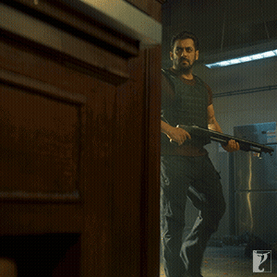 A Man Holding A Gun In A Room With A Sign That Says Exit On It GIF
