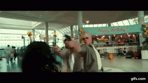 A Man Holding A Gun In Front Of A Happy Birthday Sign GIF
