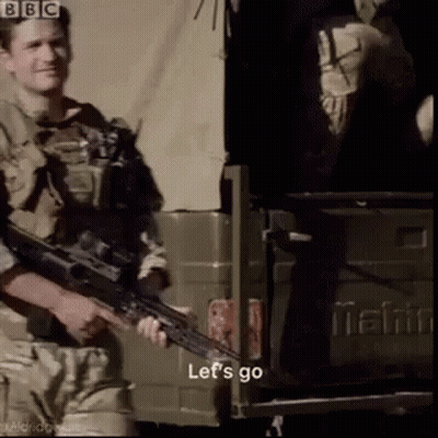 A Man Holding A Gun In Front Of A Mahindra Truck GIF