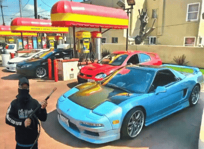 A Man Holding A Hose In Front Of A Car With A License Plate That Says California GIF