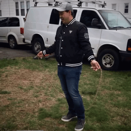 A Man Holding A Jump Rope In Front Of A White Van With The Number 8 On It GIF