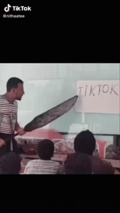 A Man Holding A Large Knife In Front Of A White Board That Says Tiktok GIF