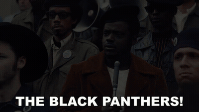 A Man Holding A Microphone In Front Of A Crowd With The Words The Black Panthers Below Him GIF