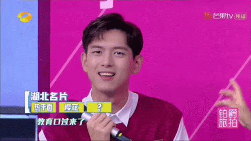 A Man Holding A Microphone In Front Of A Purple Background With Chinese Writing GIF