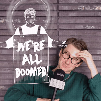 A Man Holding A Microphone In Front Of A Sign Saying We 'Re All Doomed GIF