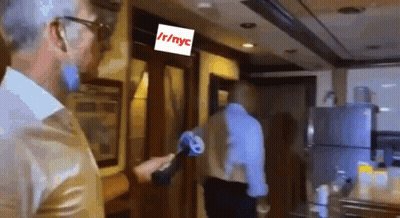 A Man Holding A Microphone In Front Of A Sign That Says Nyc GIF