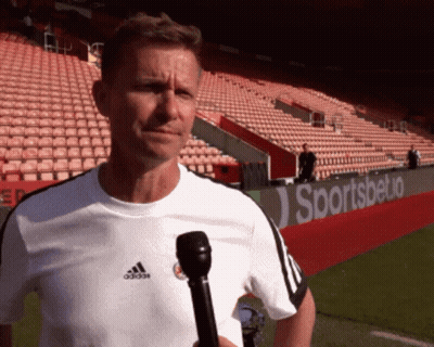 A Man Holding A Microphone In Front Of A Sportsbetio Ad GIF