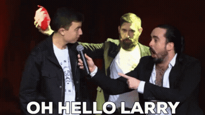 A Man Holding A Microphone Is Pointing At Another Man With The Words Oh Hello Larry Above Him GIF