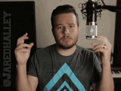 A Man Holding A Microphone With The Words @Cordhalley Behind Him GIF