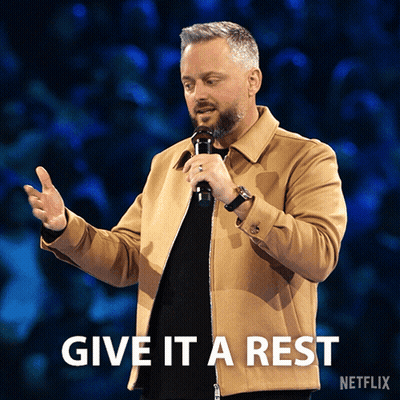 A Man Holding A Microphone With The Words Give It A Rest Written Below Him GIF