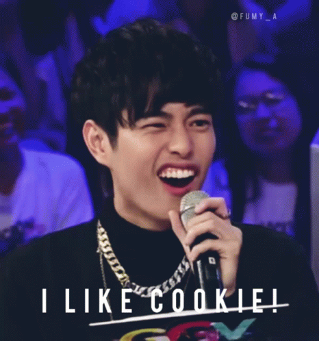 A Man Holding A Microphone With The Words " I Like Cookie " Behind Him GIF