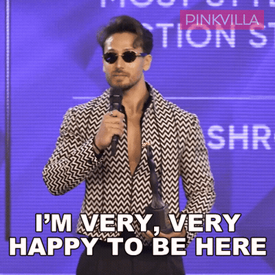 A Man Holding A Microphone With The Words I 'M Very Very Happy To Be Here GIF
