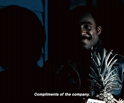 A Man Holding A Pineapple And A Card That Says Compliments Of The Company On It GIF