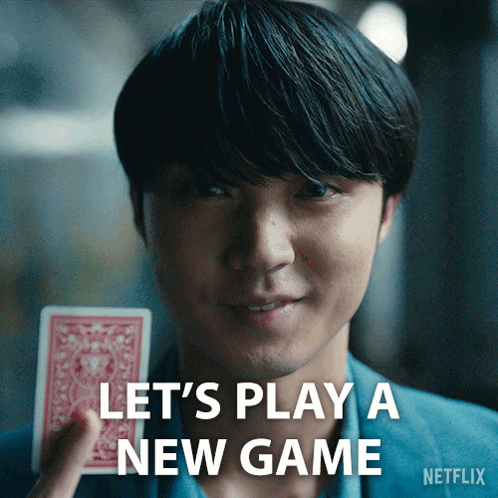 A Man Holding A Playing Card With The Words Let 'S Play A New Game Written Below Him GIF
