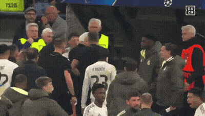 A Man Holding A Red Card Stands In A Crowd Of People GIF