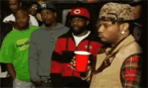 A Man Holding A Red Cup In Front Of A Crowd Of People GIF