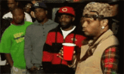 A Man Holding A Red Cup Stands In A Crowd Of People GIF