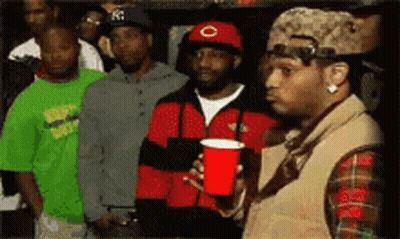 A Man Holding A Red Cup Stands In Front Of A Crowd Of People GIF