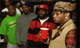 A Man Holding A Red Cup Stands In Front Of A Crowd Of People GIF