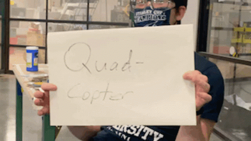 A Man Holding A Sign That Says Quad Copter On It GIF
