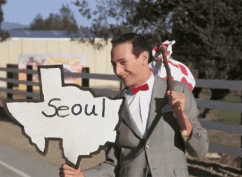 A Man Holding A Sign That Says Seoul GIF