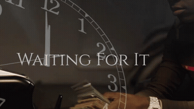 A Man Holding A Stack Of Money In Front Of A Clock That Says " Waiting For It " GIF