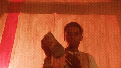 A Man Holding A Stack Of Money In Front Of A Red Background GIF
