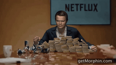 A Man Holding A Stack Of Money In Front Of A Sign That Says " Netflix " GIF