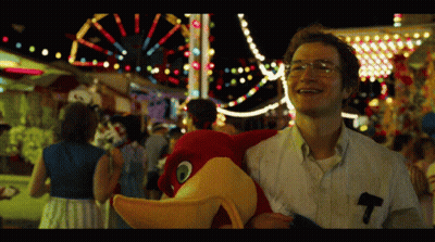 A Man Holding A Stuffed Animal With The Letter T On His Pocket GIF