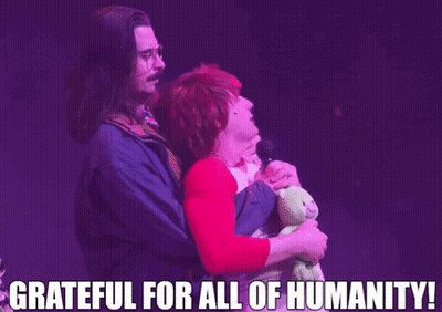 A Man Holding A Teddy Bear And A Woman Holding A Microphone With The Words Grateful For All Of Humanity GIF