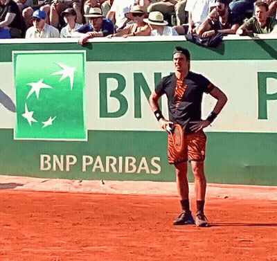 A Man Holding A Tennis Racquet In Front Of A Bnp Pariba Sign GIF