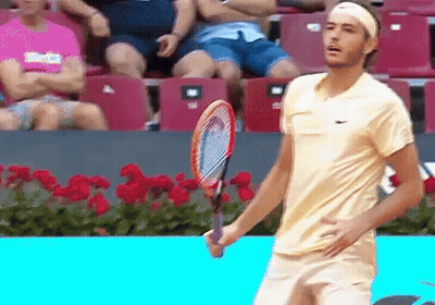 A Man Holding A Tennis Racquet In Front Of A Crowd GIF