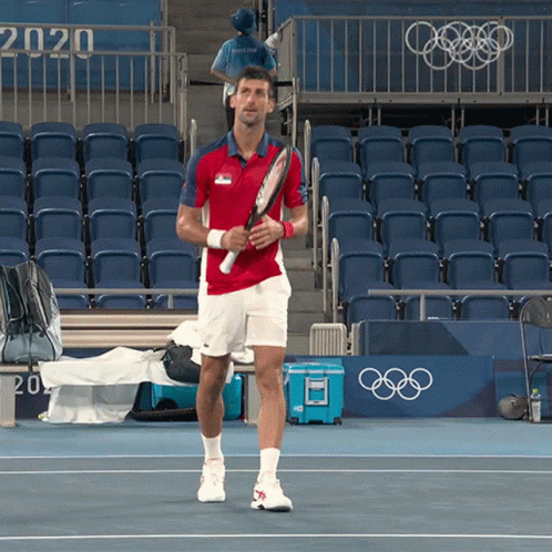 A Man Holding A Tennis Racquet In Front Of A Sign That Says 2020 On It GIF