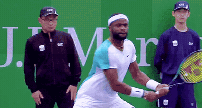 A Man Holding A Tennis Racquet In Front Of A Sign That Says J.m. GIF