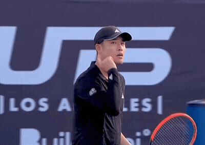 A Man Holding A Tennis Racquet In Front Of A Sign That Says U.s. GIF