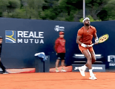 A Man Holding A Tennis Racquet In Front Of A Wall That Has Reale Mutua Written On It GIF