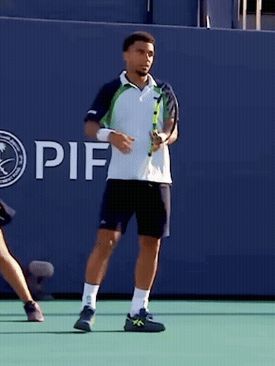 A Man Holding A Tennis Racquet In Front Of A Wall That Says If On It GIF