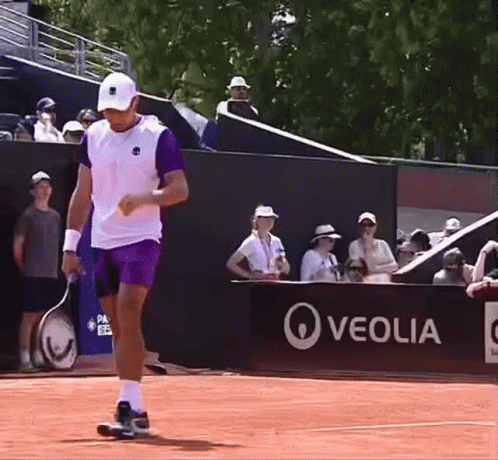 A Man Holding A Tennis Racquet On A Court In Front Of A Sign That Says Veolia GIF