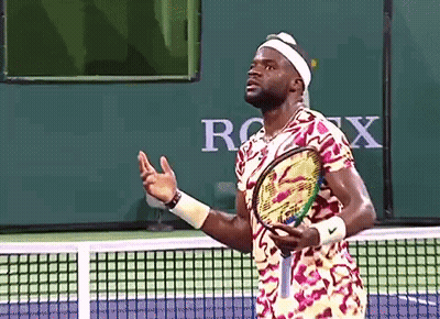 A Man Holding A Tennis Racquet On A Tennis Court In Front Of A Sign That Says Rolex GIF