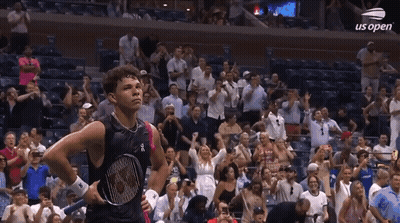 A Man Holding A Tennis Racquet Stands In Front Of A Crowd At Us Open GIF