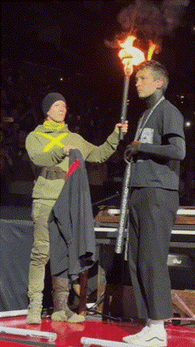 A Man Holding A Torch Stands Next To A Woman Holding A Jacket GIF